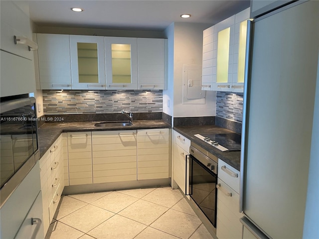 kitchen with light tile patterned flooring, sink, white cabinets, oven, and fridge