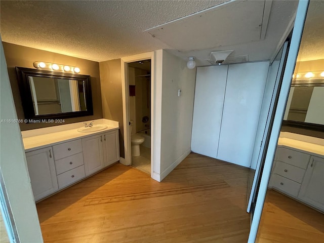 bathroom featuring wood-type flooring, vanity, a textured ceiling, and toilet