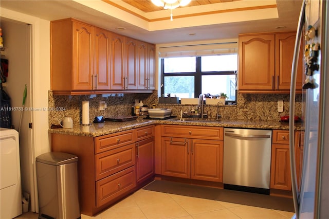 kitchen with stainless steel appliances, tasteful backsplash, sink, and a tray ceiling