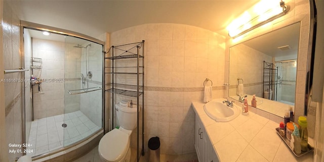 bathroom featuring vanity, a shower with door, toilet, and tile walls