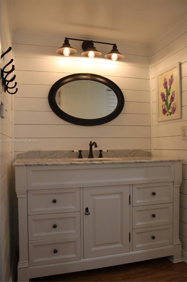 bathroom featuring wood-type flooring, wood walls, and vanity