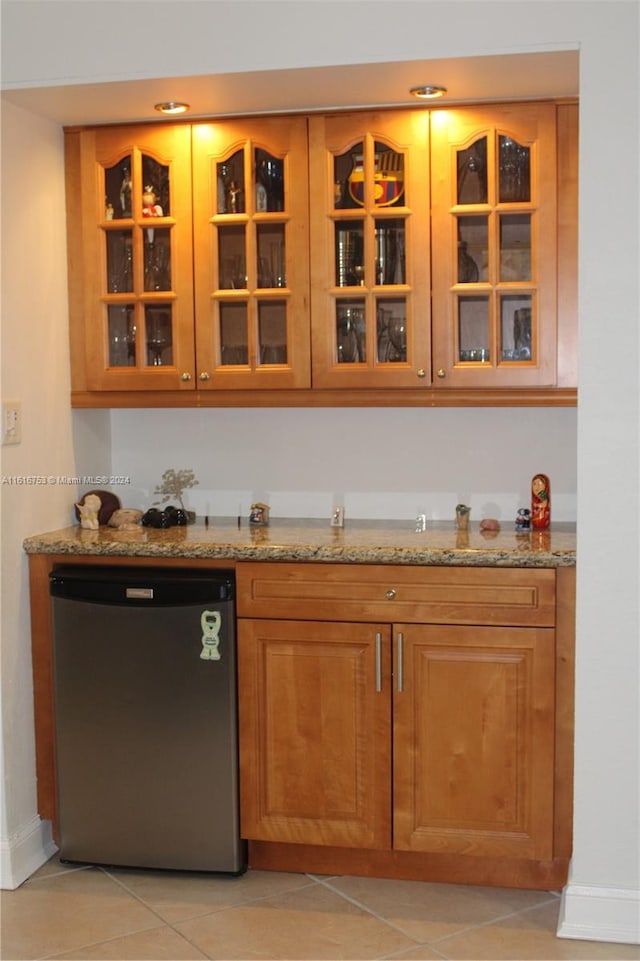 bar with light tile patterned flooring, stainless steel dishwasher, and light stone countertops