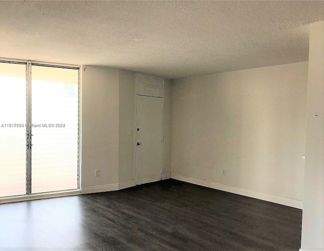 empty room with a textured ceiling and dark hardwood / wood-style flooring