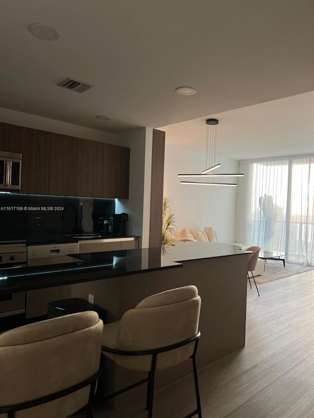 kitchen featuring dark brown cabinets, light wood-type flooring, and a kitchen breakfast bar