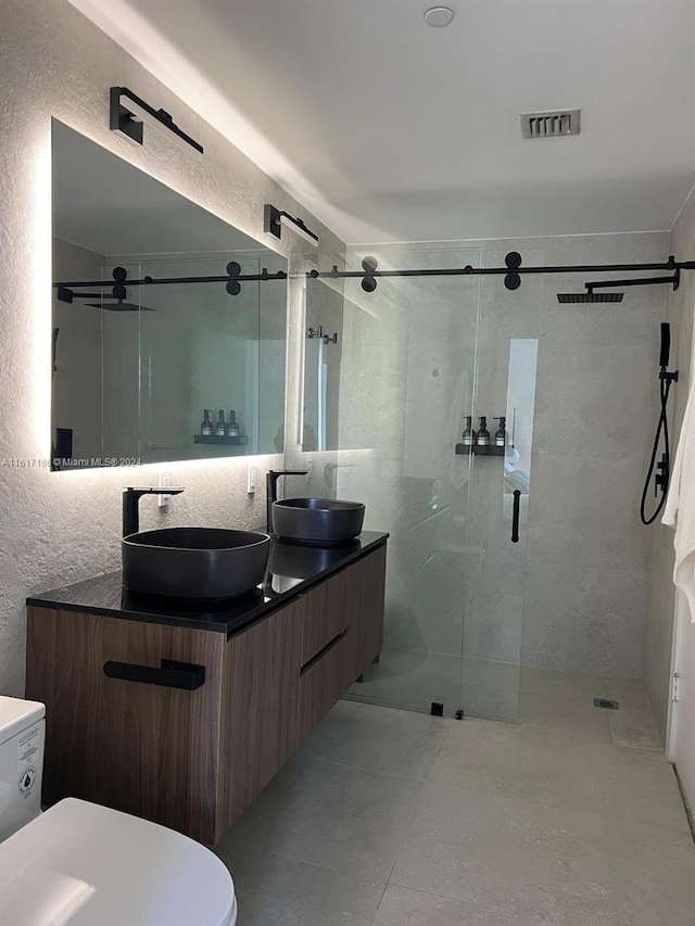 bathroom featuring walk in shower, double vanity, tile patterned floors, and toilet