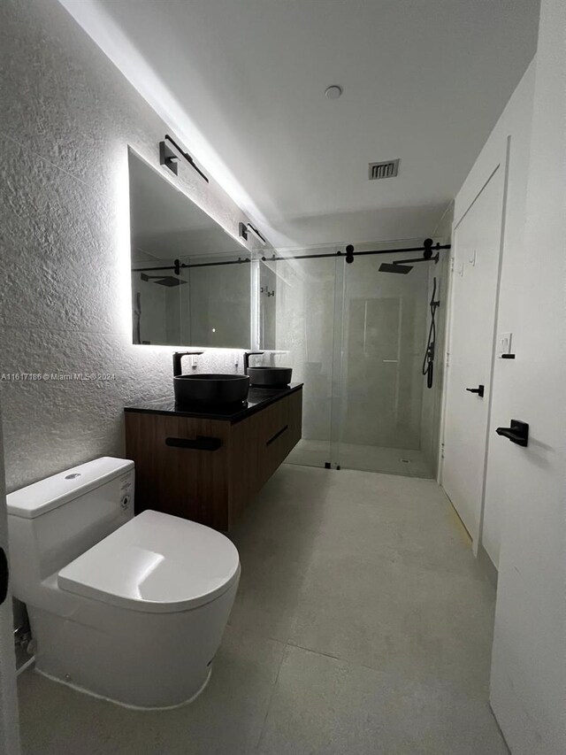 bathroom with vanity, a shower with door, and toilet