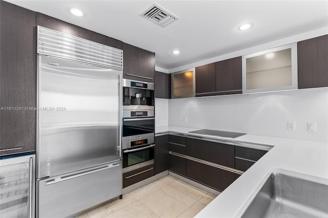 kitchen featuring appliances with stainless steel finishes, beverage cooler, light tile patterned floors, and dark brown cabinetry