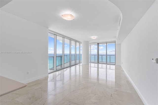 tiled spare room with a wall of windows, plenty of natural light, and a water view