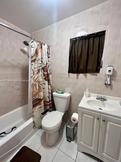 full bathroom with vanity, tile walls, tile patterned floors, shower / bath combo, and toilet