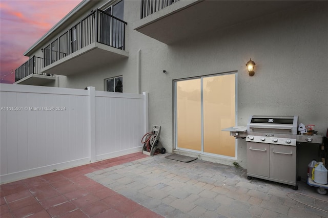 patio terrace at dusk with area for grilling and a balcony