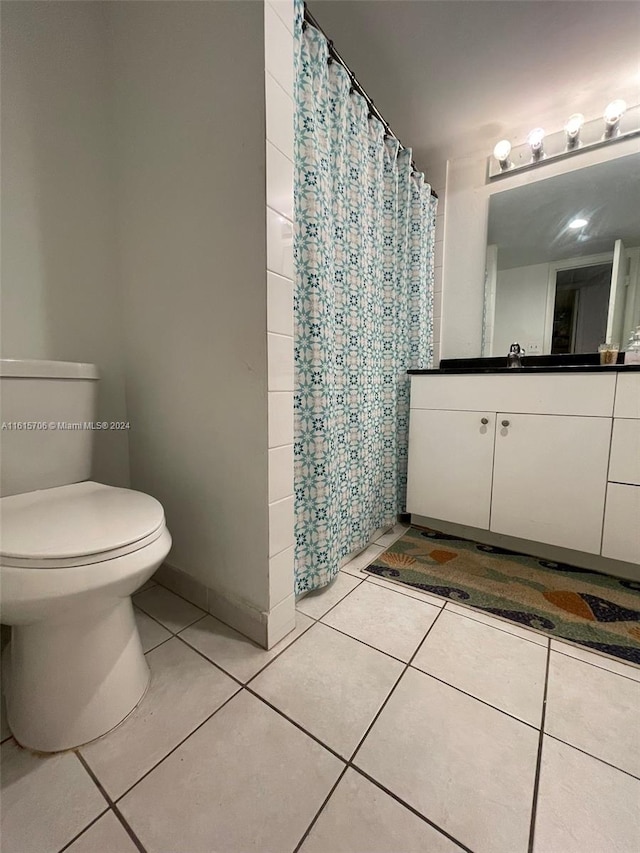 bathroom featuring vanity, toilet, tile patterned floors, and tile walls