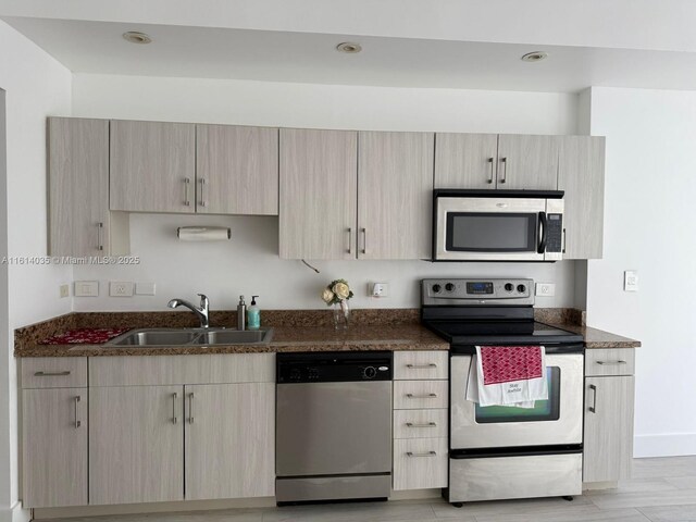 kitchen featuring light stone countertops, sink, light hardwood / wood-style floors, and appliances with stainless steel finishes