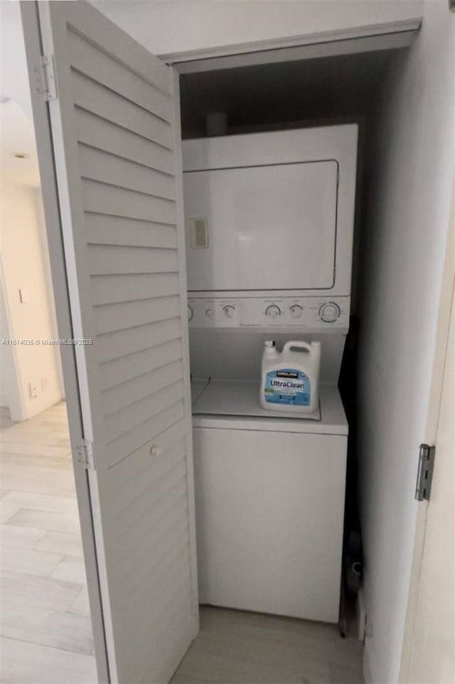 laundry area featuring stacked washer and clothes dryer and light wood-type flooring