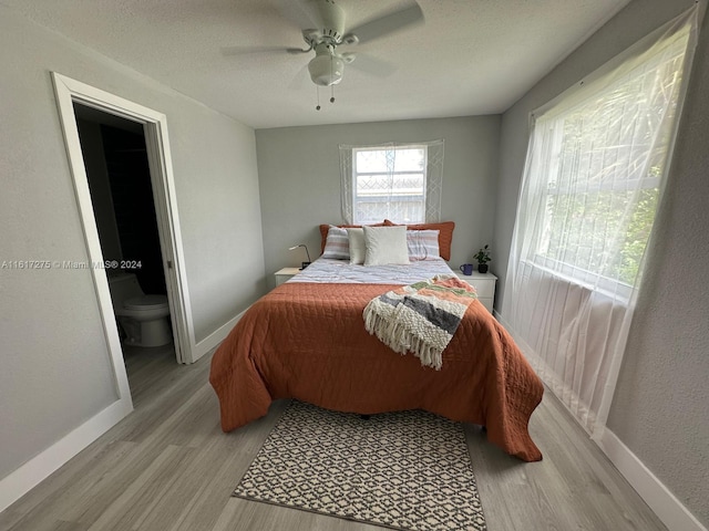 bedroom featuring ensuite bathroom, light hardwood / wood-style flooring, and ceiling fan