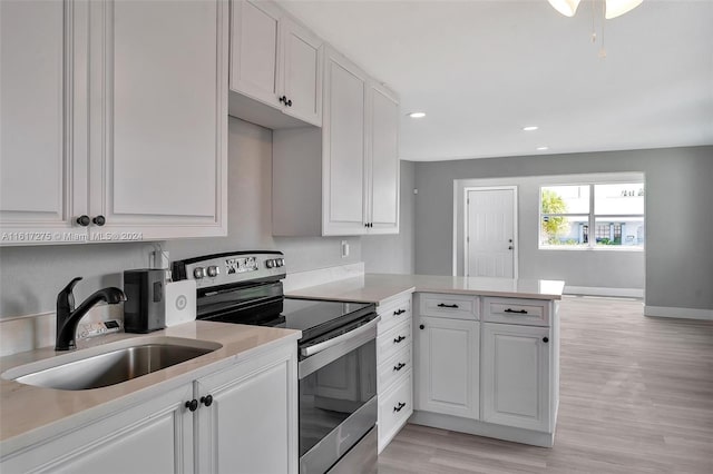 kitchen featuring white cabinets, sink, stainless steel electric range oven, light hardwood / wood-style floors, and kitchen peninsula