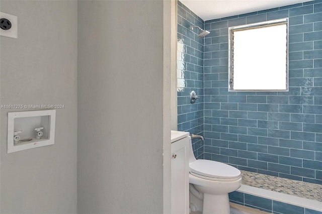 bathroom with vanity, toilet, and a tile shower