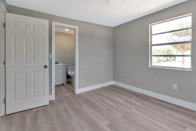 unfurnished bedroom with light wood-type flooring, ensuite bath, and sink