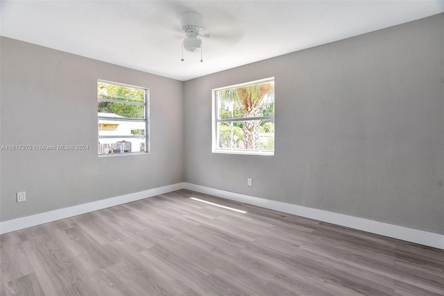 empty room with ceiling fan, plenty of natural light, and light hardwood / wood-style floors