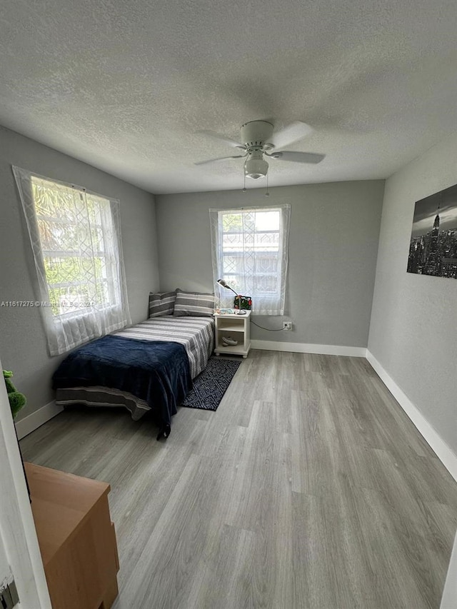 bedroom featuring ceiling fan, light hardwood / wood-style floors, and a textured ceiling