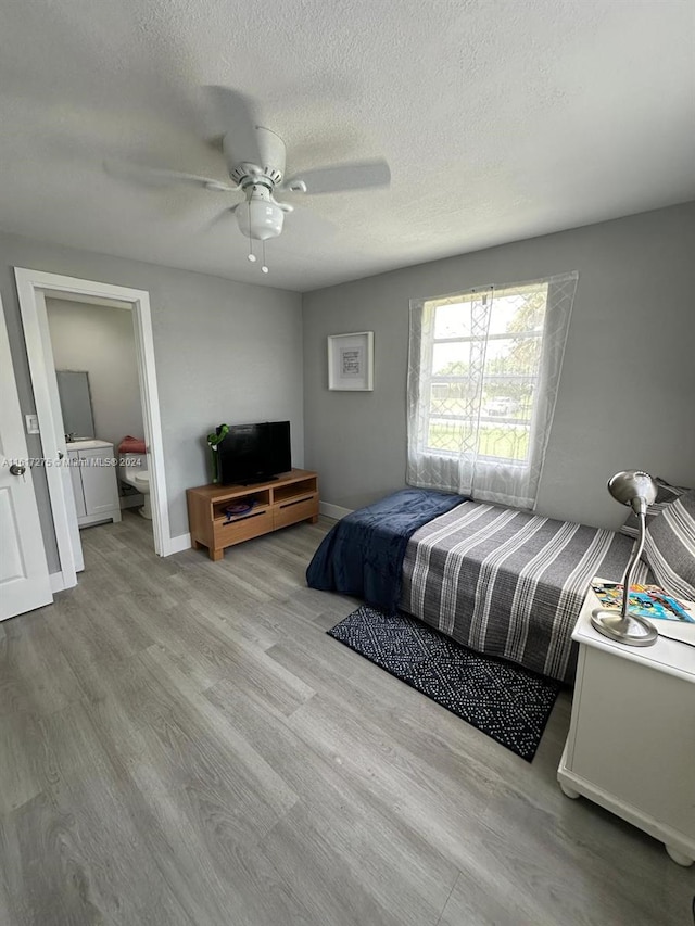 bedroom with ceiling fan, light wood-type flooring, and a textured ceiling