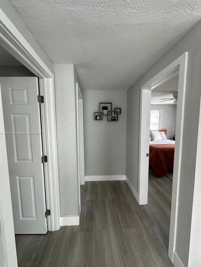 hallway featuring a textured ceiling and dark hardwood / wood-style floors