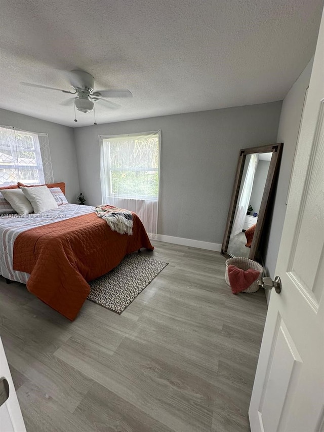 bedroom with ceiling fan, light hardwood / wood-style floors, and a textured ceiling