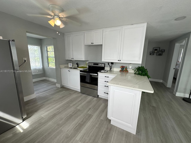 kitchen with a textured ceiling, light wood-type flooring, kitchen peninsula, and stainless steel appliances