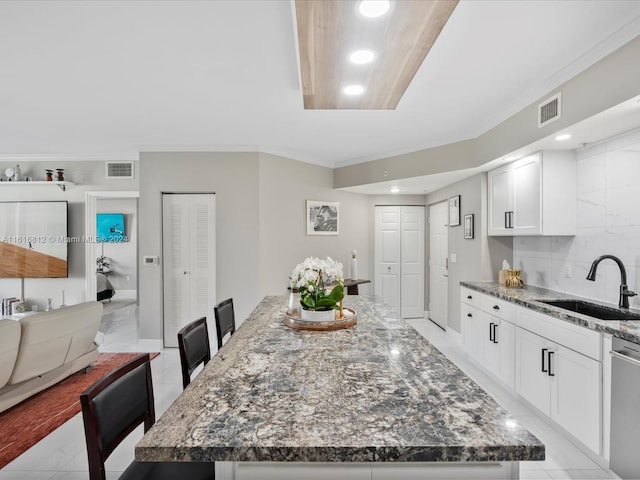 kitchen with dishwasher, a center island, dark stone counters, white cabinets, and sink