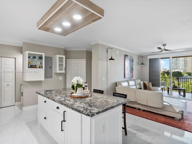 kitchen with ceiling fan, a center island, dark stone countertops, and white cabinetry