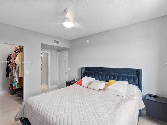 bedroom featuring ceiling fan, a walk in closet, a textured ceiling, and a closet