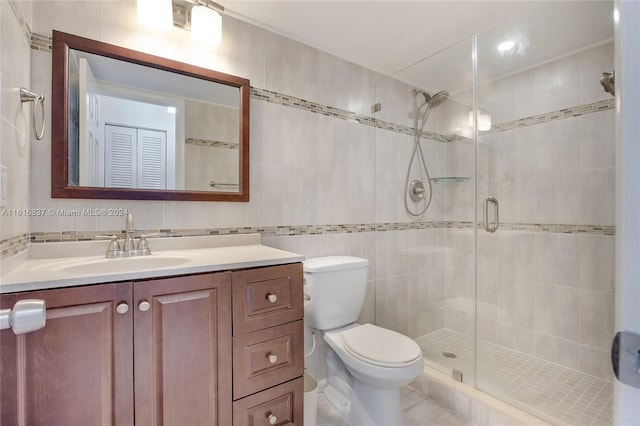 bathroom with an enclosed shower, tile patterned floors, toilet, tile walls, and vanity