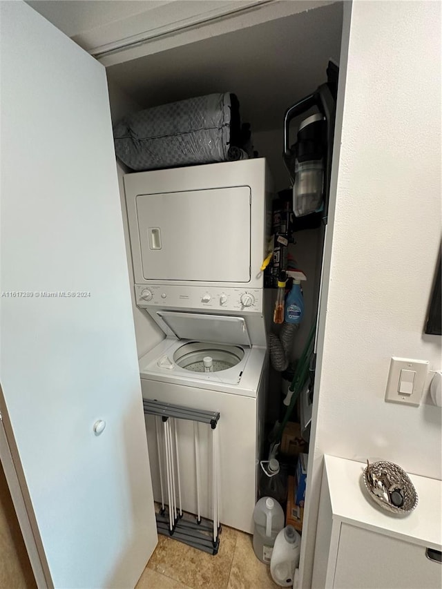 washroom featuring stacked washing maching and dryer and light tile patterned floors