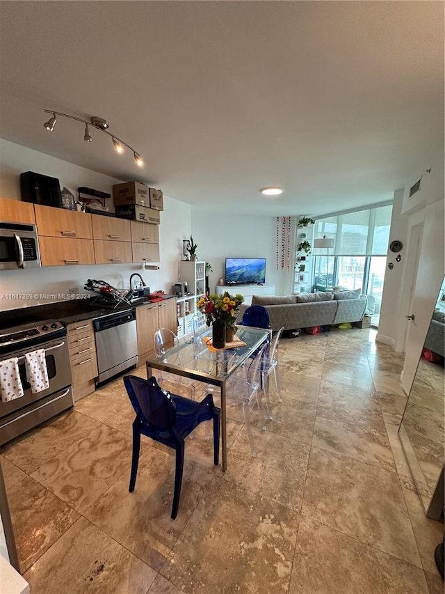 kitchen with floor to ceiling windows, light tile patterned floors, stainless steel appliances, track lighting, and light brown cabinetry