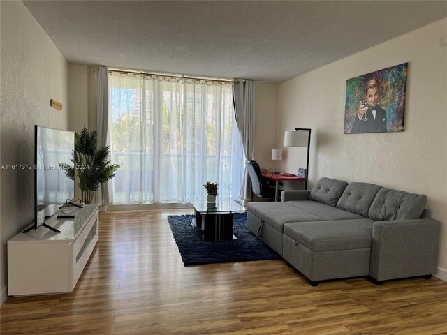 living area with a textured wall, a textured ceiling, and wood finished floors