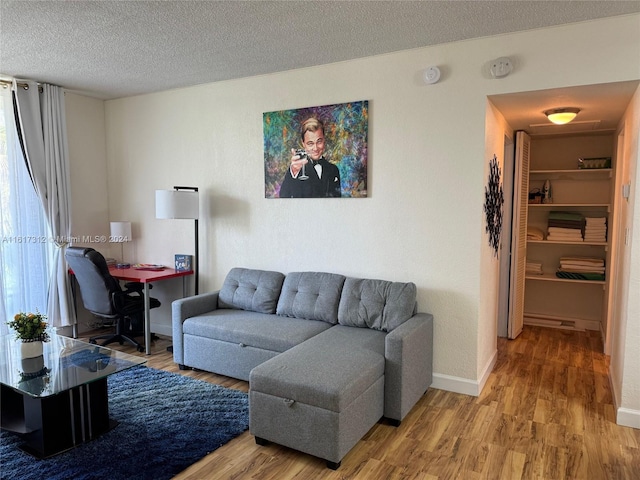 living area featuring a textured ceiling, wood finished floors, and baseboards