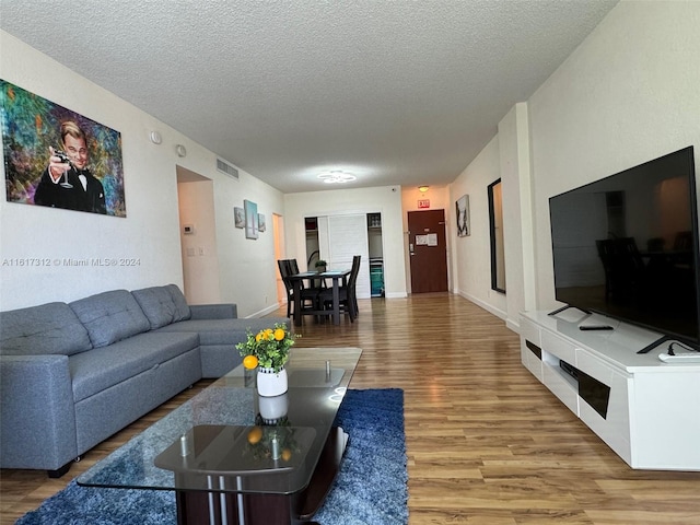 living area with visible vents, a textured ceiling, baseboards, and wood finished floors