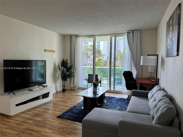 living room with a textured wall, expansive windows, a textured ceiling, wood finished floors, and baseboards