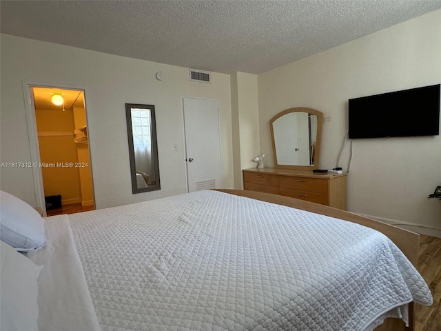 bedroom with a textured ceiling, wood finished floors, and visible vents