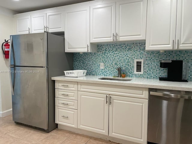 kitchen with stainless steel appliances, light countertops, white cabinetry, and a sink