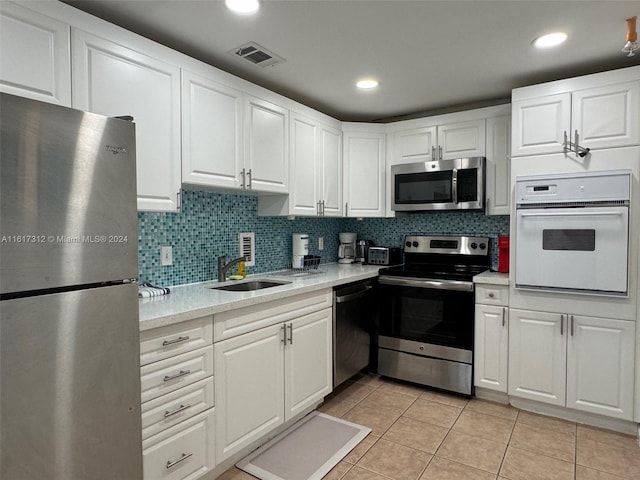 kitchen featuring tasteful backsplash, visible vents, appliances with stainless steel finishes, light countertops, and a sink