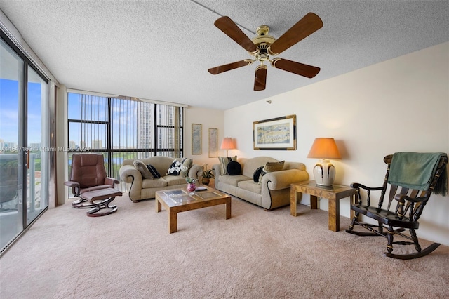 living room featuring ceiling fan, light colored carpet, a textured ceiling, and a wall of windows