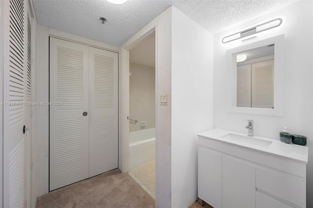 bathroom featuring a textured ceiling, vanity, and a bathtub