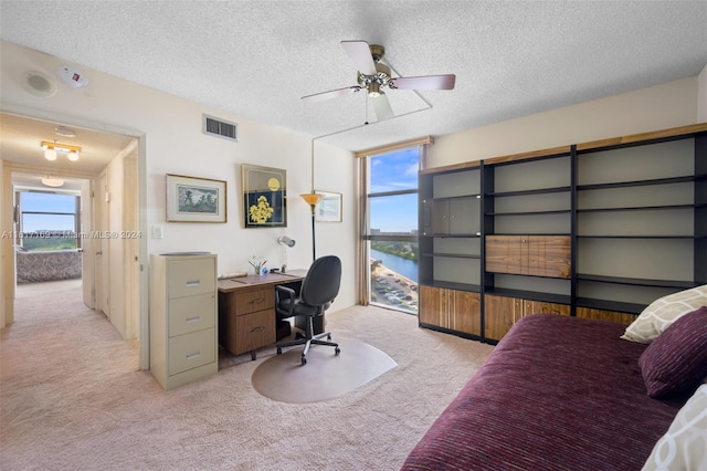 carpeted office space with ceiling fan, a water view, and a textured ceiling