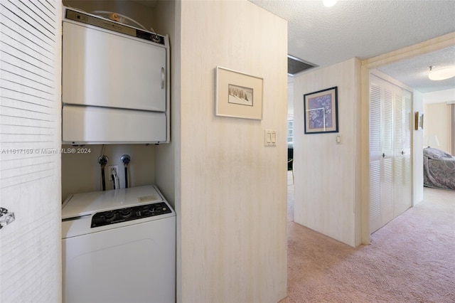 laundry room with stacked washer / dryer, water heater, light colored carpet, and a textured ceiling