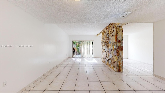 tiled empty room featuring a textured ceiling