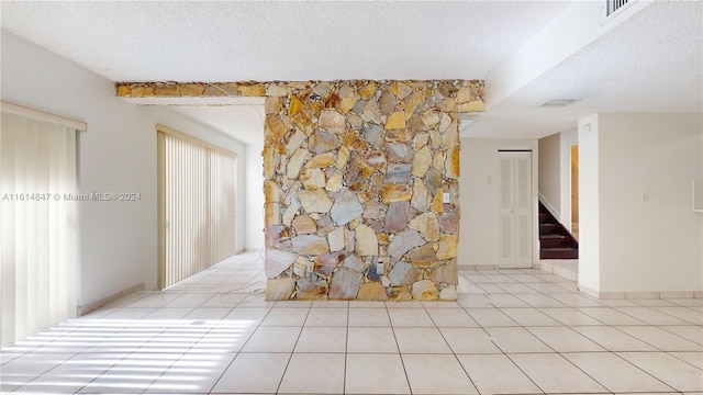 unfurnished living room with light tile patterned flooring and a textured ceiling