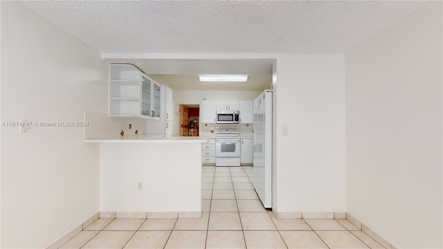 kitchen featuring range, a textured ceiling, light tile patterned flooring, and white cabinets