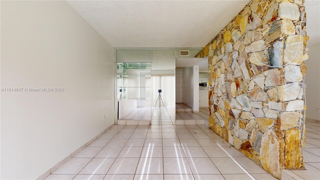 hallway featuring a textured ceiling and light tile patterned floors