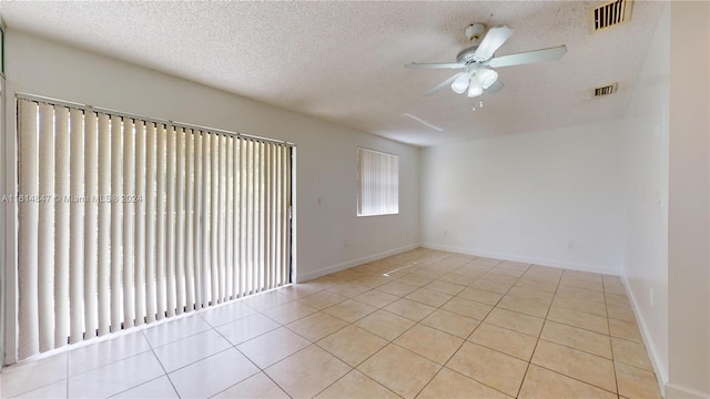 empty room featuring a textured ceiling, ceiling fan, and light tile patterned floors