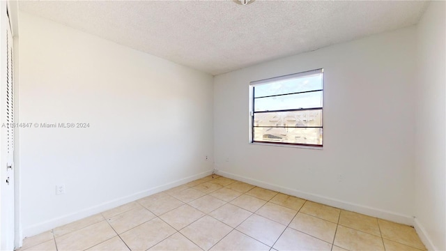 tiled empty room featuring a textured ceiling